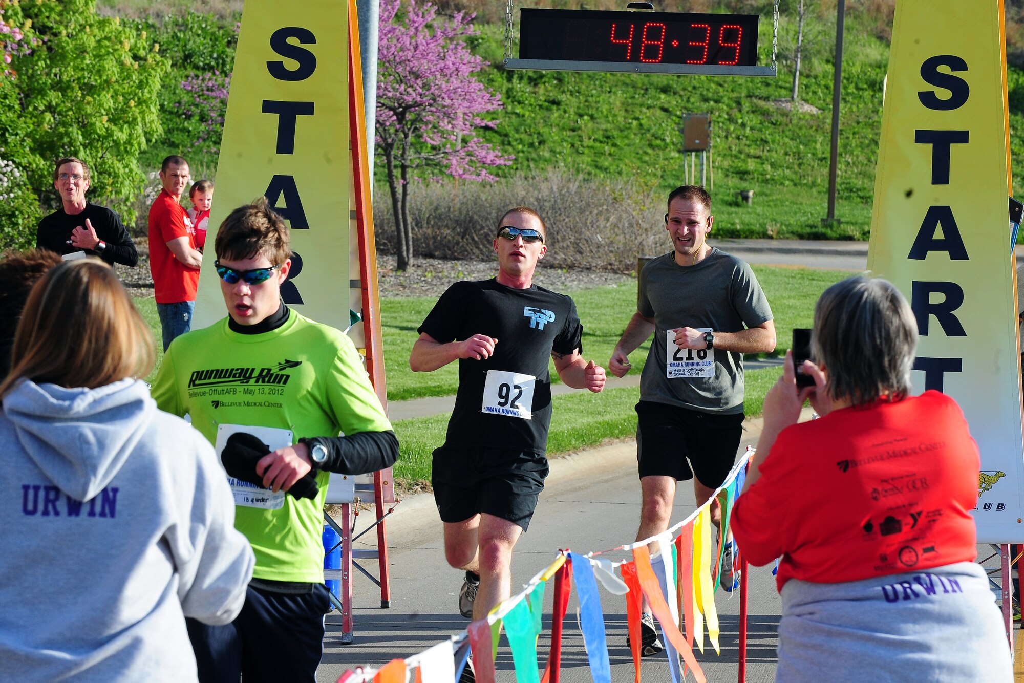 The first wave of runners cross the finish line at the Bellevue Lied Activity Center following their seven-mile Runway Run hosted annually by the Bellevue and Offutt Air Force Base community on May 12.  The Runway Run is a popular run garnering hundreds of participants every year.  (U.S. Air Force photo by Josh Plueger/Released)