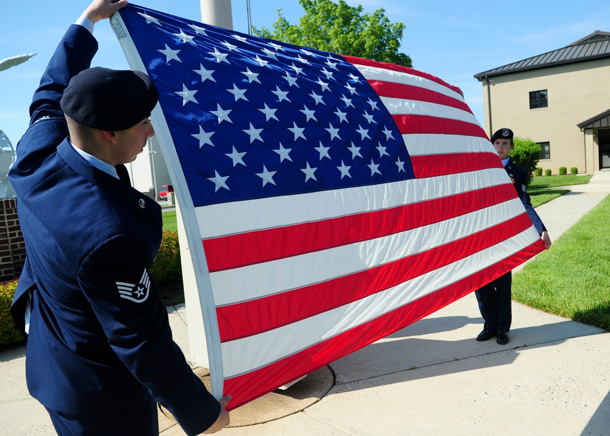 Staff Sgt. Adam Paini and Staff Sgt. Christine Campos, both of the 436th Security Forces Squadron, prepare to fold the flag during a retreat ceremony May 17, 2013, at the wing headquarters building on Dover Air Force Base, Del. The ceremony was held to celebrate National Police Week and to honor fallen law enforcement officers and their families. (U.S. Air Force photo/Airman 1st Class Ashlin Federick)