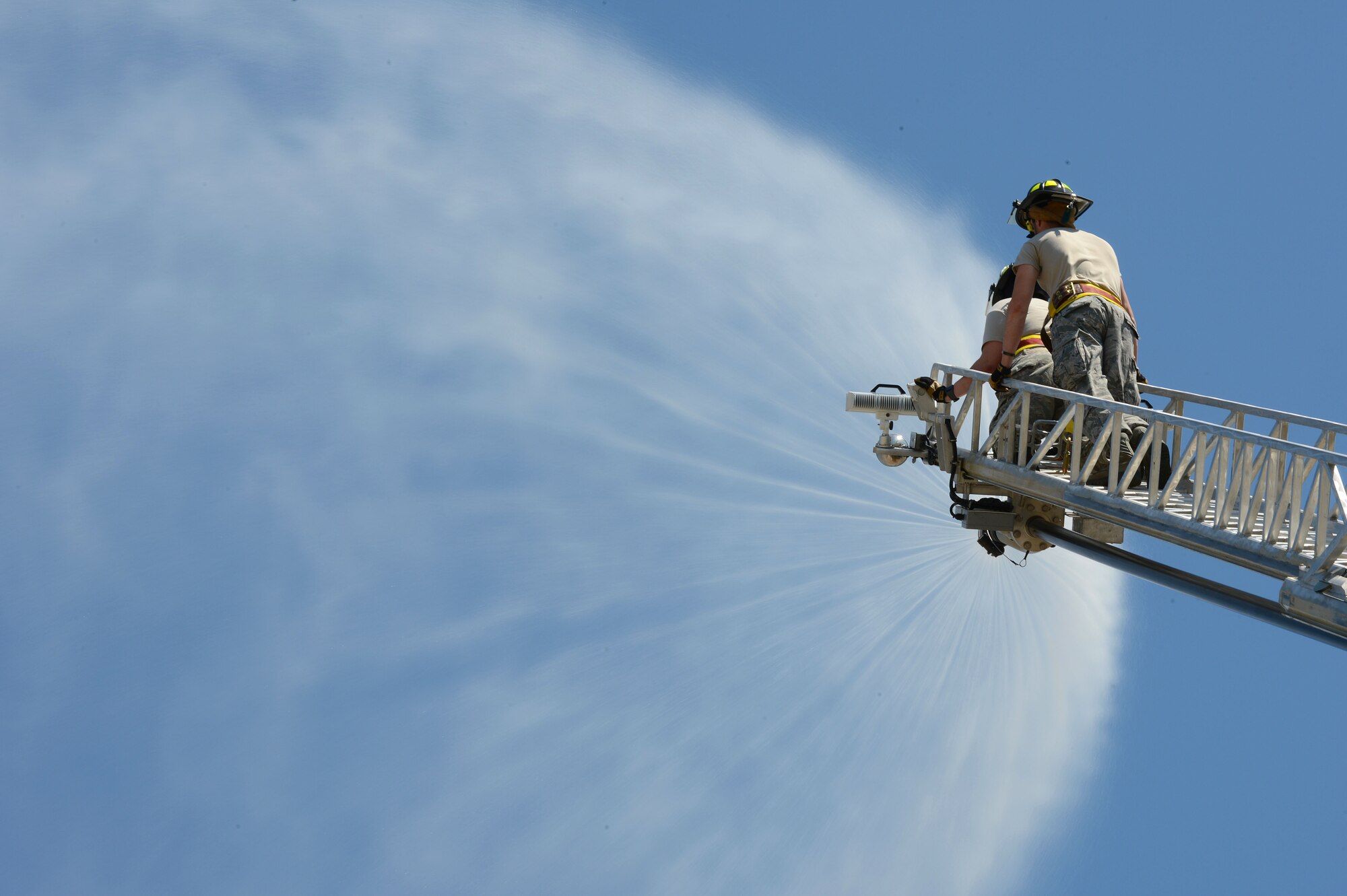 U. S. Air Force Airman 1st Class Zach Fowler and Senior Airman Charles Maxwell, both 20th Civil Engineer squadron fire department firefighters, spray water from a hose while practicing a ladder climb at Shaw Air Force Base, S.C., May 16, 2013.  The firefighters train weekly on structural firefighting, aircraft firefighting, hazardous materials, rescue operations including confined space and also vehicle extrication. (U.S. Air Force photo by Airman 1st Class Nicole Sikorski/Released).