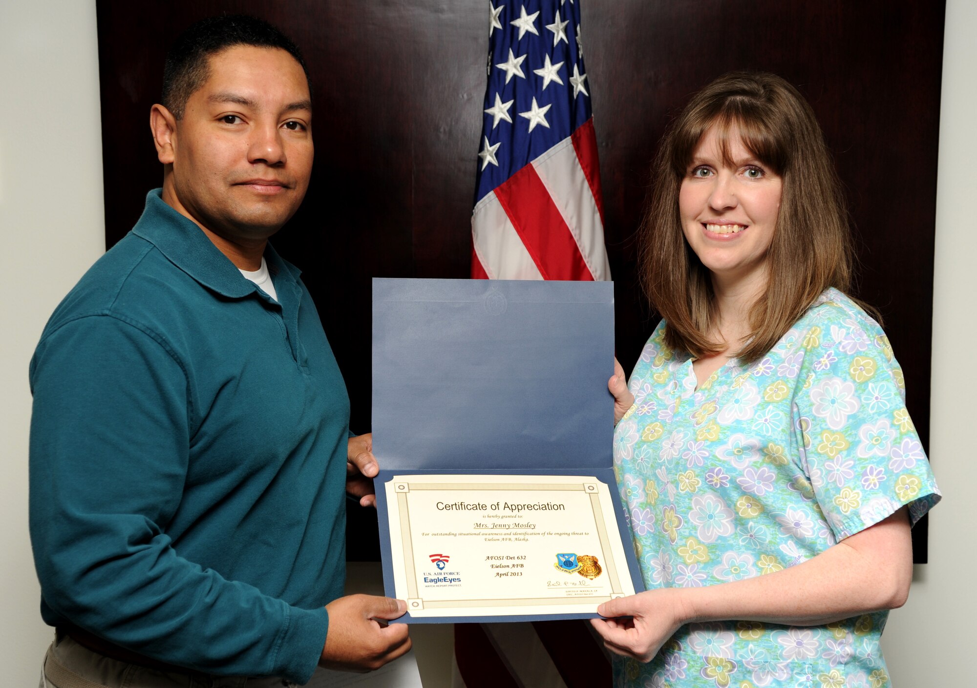 Special Agent Luis Sanjur, Office of Special Investigations Detachment 632 superintendent, presents an Eagle Eyes Certificate of Appreciation to Jenny Mosley, wife of Tech. Sgt. Christopher Mosley, 354th Fighter Wing, May 17, 2013, Eielson Air Force Base, Alaska. Mosley reported a suspicious person during an operational readiness exercise in April, alerting Security Forces personnel and preventing a possible surveillance collection opportunity. (U.S. Air Force photo by Staff Sgt. Jim Araos/Released)
