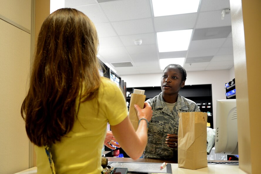 U.S. Air Force Senior Airman Erika McCrea, 20th Medical Group pharmacy technician, hands medication to a patient at Shaw Air Force Base, S.C., May 16, 2013.  McCrea handles 500 different types of medication that the pharmacy stocks, dispenses 5,000 prescriptions a week and helps serve 31,000 beneficiaries, which include active-duty service members, dependents and retirees. (U.S. Air Force photo by Airman 1st Class Nicole Sikorski/Released).