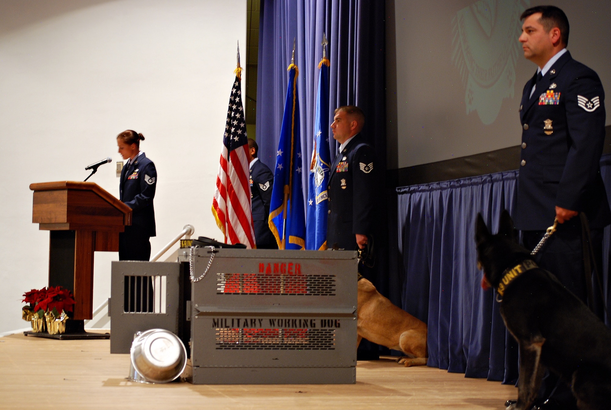 Two 21st Security Forces Squadron Airmen with their working dogs stand guard over a symbolic empty kennel during military working dog Aio’s memorial ceremony May 14. Service members and civilians stood at attention while the 21st Security Forces Squadron honored the passing of MWD Aio and recognized four military working dogs retiring from active service. (U.S. Air Force photo/Michael Golembesky)