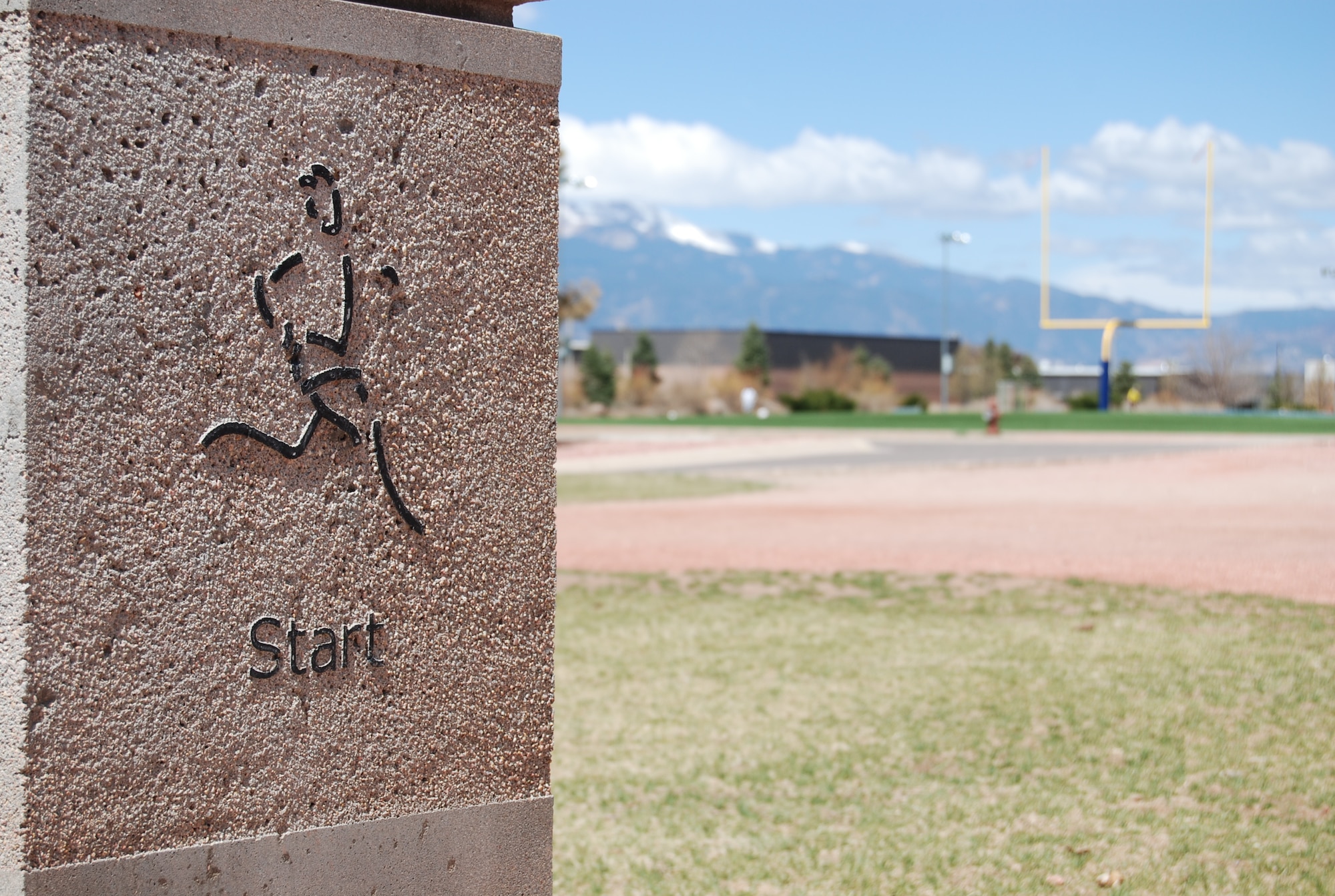 A cement marker shows the starting point and meeting place for the Peterson Running Club that meets at 11:30 a.m. every Tuesday. The route marker is located along the gravel footpath between buildings 404 and 425, and runners can choose from a 3k, 5k or 10k route. (U.S. Air Force photo/Michael Golembesky)