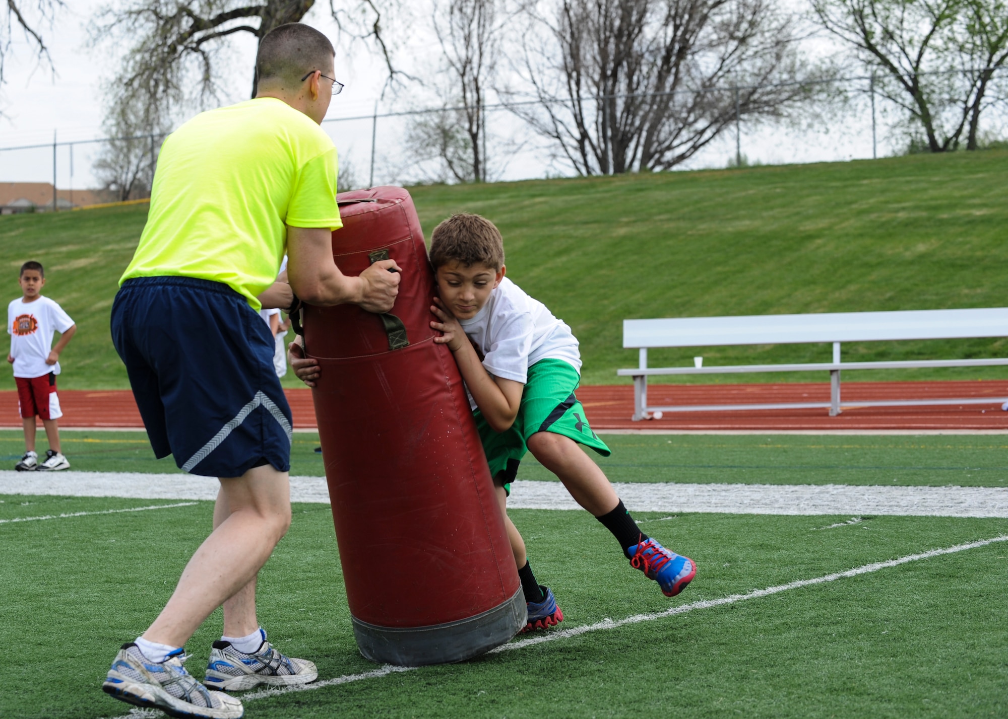 Darren Scott takes a hit from a 16Ways football camp participant during a form tackling drill May 18, 2013, at the Aurora Public Stadium, Aurora, Colo. Scott, an airman first class with the 460th Space Wing Public Affairs Office, was one of about 30 volunteers from Buckley Air Force Base, Colo. The camp, hosted by Denver Bronco Wesley Woodyard’s 16Ways Foundation, focused on basic football fundamentals, teamwork and anti-bullying. (U.S. Air Force photo by Staff Sgt. Christopher Gross)