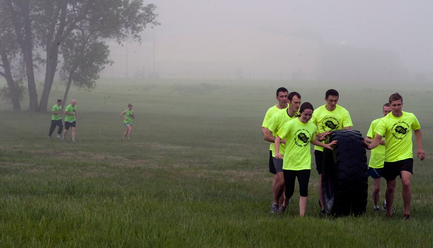 Airmen from the 350th Air Refueling Squadron work together to move a tire May 17, 2013, McConnell Air Force Base, Kan. The tire had to be rolled approximately 50 yards and back to complete the obstacle. This event was a part of the annual Amazing Race. (U.S. Air Force photo/Airman 1st Class Colby L. Hardin)