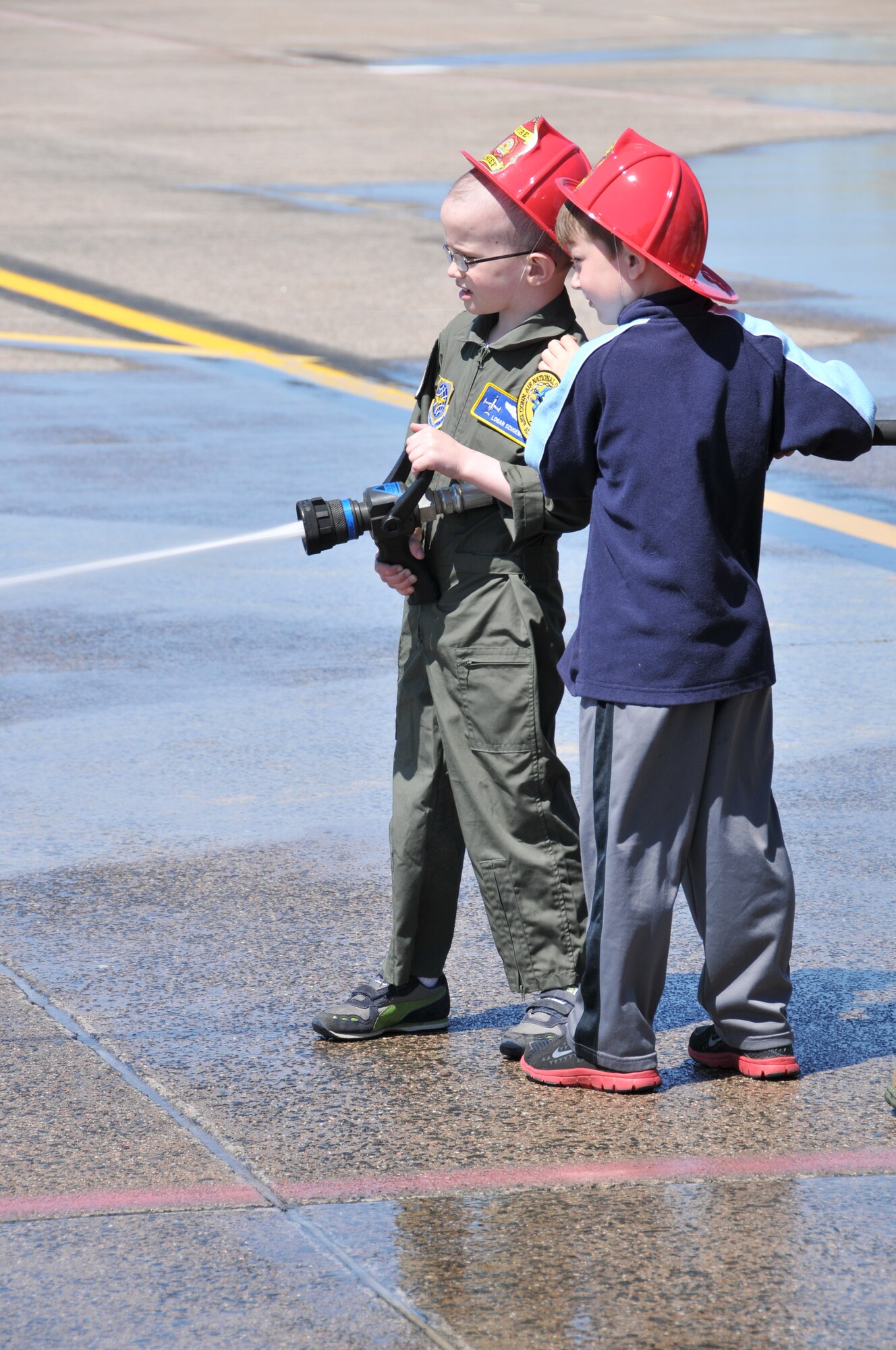 Logan Schoenhardt and his friend, Andrew Kerwin,  spray the fire hose on the ramp at Bradley as they pretend to be military firefighters during the Pilot for A Day Program at Bradley Air National Guard Base, East Granby, Conn., May 3, 2013. (Air National Guard photo by Senior Airman Jennifer Pierce/Released)