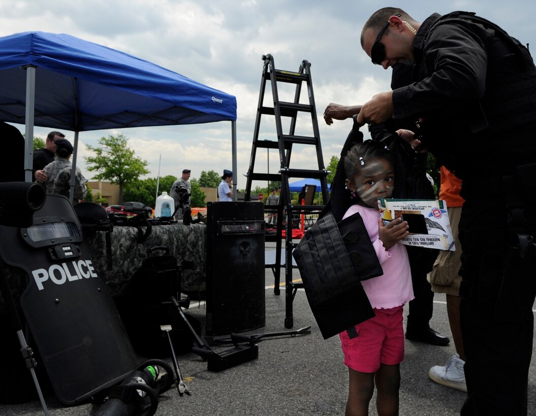 An 11th Security Forces Squadron Air Force civilian police officer assists Shiloh as she tries on a bulletproof vest during the National Police Week Tactical First Responders Demonstration on May 17, 2013 at Joint Base Andrews, Md. (U.S. Air Force photo/ Airman 1st Class Nesha Humes)