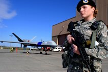Staff Sgt. Courtney Cambio, 319th Security Forces Squadron, provides direct security for a U.S. Customs and Border Protection MQ-9 Predator B being used as a static display during the 319th Air Base Wing assumption-of-command ceremony on May 15, 2013, at Grand Forks Air Force Base, N.D. The multi-million dollar aircraft is a long-endurance, medium-altitude unmanned aircraft system for surveillance and reconnaissance missions. (U.S. Air Force photo/Staff Sgt. Luis Loza Gutierrez)
