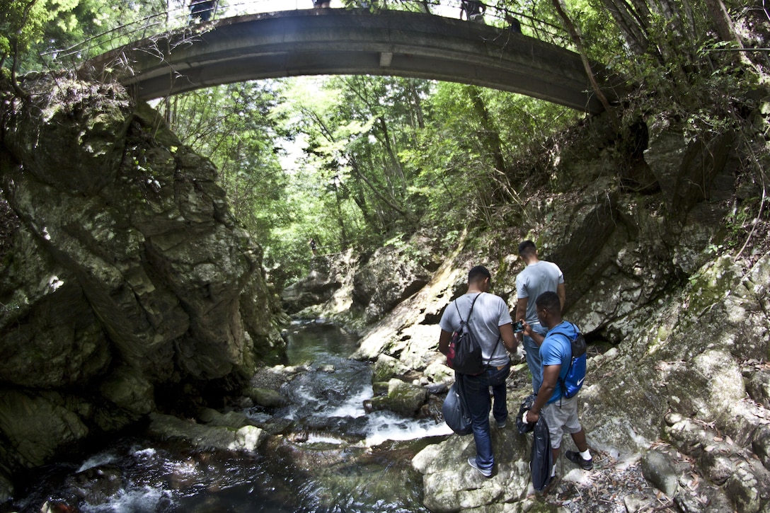 Single Marine Program cleanup event participants take photos and pick up trash while walking through one of the trails at Futashika Umezu Falls and park, May 17, 2013. Volunteers split into several groups in order to cover more area within the park and falls. Ryan Leming, installation solid-waste manager and Japan resident, facilitated the interaction with the local community. Leming also mentioned his desire to make this cleanup event a tradition for every spring and fall.