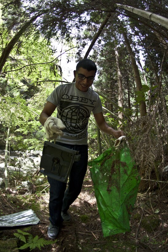 A Single Marine Program cleanup event participant picks up trash while walking through one of the trails at Futashika Umezu Falls and park, May 17, 2013. “I like to volunteer to a cause,”said Maria Molinalemus, SMP river cleanup participant. “If you can’t give out money, then you have to give a piece of yourself and I think helping out the community is the best thing. ... It’s about helping out.”