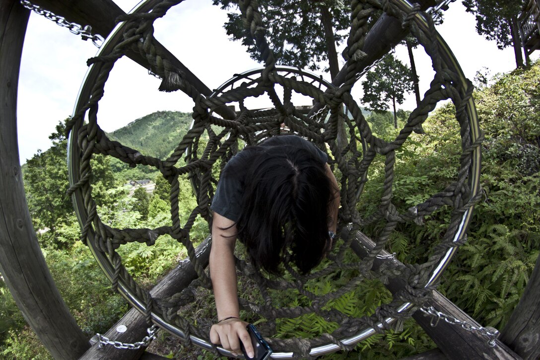 Maria Molinalemus, Single Marine Program cleanup event participant, crawls through part of an obstacle course located at Futashika Umezu Falls and park, May 17, 2013. Participants spent the later half of the trip enjoying a barbeque and exploring other areas of the park, one of which included an obstacle course with several sections that scaled up a nearby mountain.