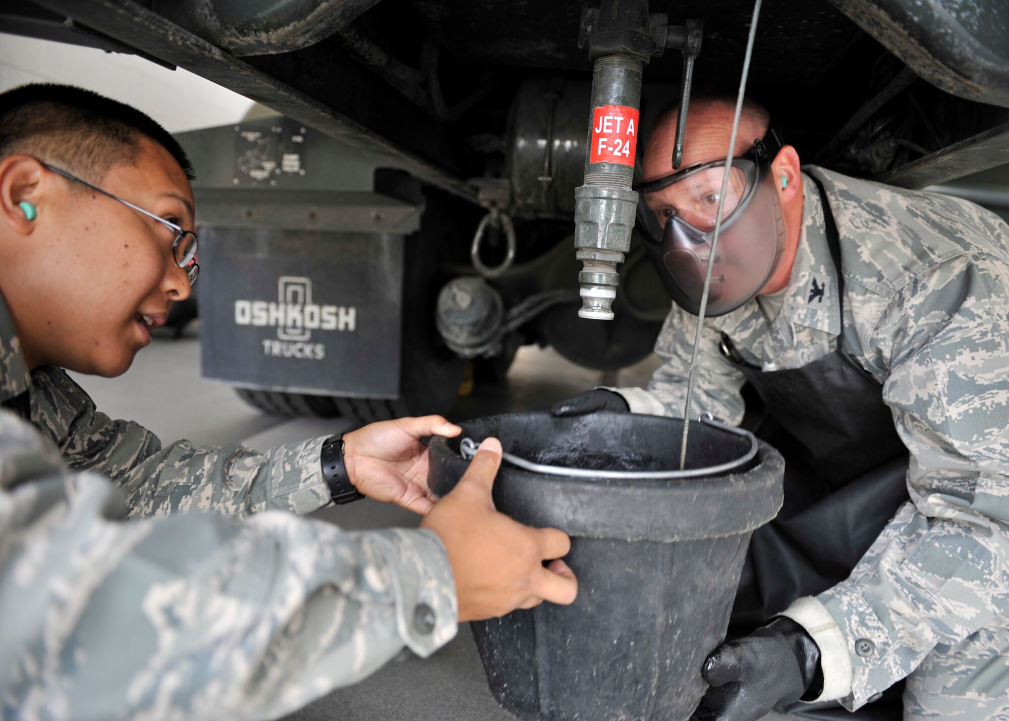 Staff Sgt. Joshua Nakao, 92nd Logistics Readiness Squadron preventative maintenance noncomissioned officer in charge, instructs Col. Konrad Klausner, 92nd Mission Support Group commander, on how to collect a fuel sample from an R11 fuel truck at Fairchild Air Force Base, Wash. May 17, 2013. The colonel will periodically participate in the work his Airmen perform to better understand the effort put into the mission. (U.S. Air Force photo by Staff Sgt. Michael Means/Released)