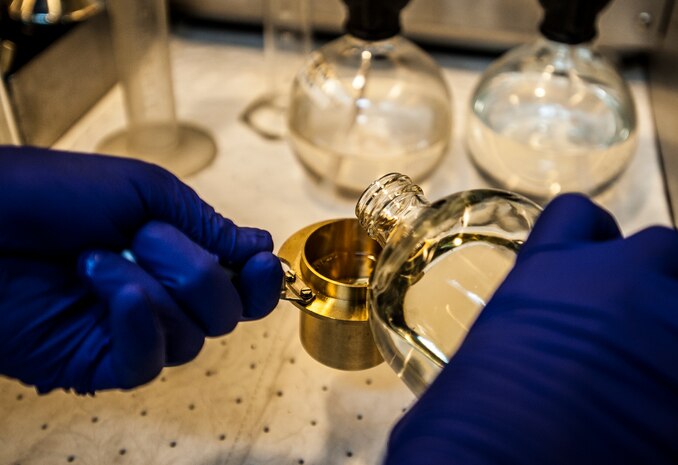Senior Airman Mark Miller, 628th Logistics Readiness Squadron Fuels Laboratory technician, pours Jet fuel into a cylinder to be used during a flash test May 10, 2013, at Joint Base Charleston – Air Base, S.C. The flash test records the temperature at which the fuel ignites. (U.S. Air Force photo/ Senior Airman Dennis Sloan)