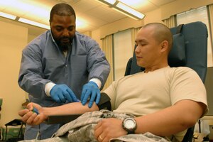 Daniel Belin, a phlebotomist from Naval Medical Center Portsmouth, draws blood from Senior Airman Jordan Young, 27th Intelligence Squadron account management technician, during an Armed Services Blood Program blood drive at Langley Air Force Base, Va., May 21, 2013. The ASBP hosts blood drives monthy to encourage military and civilian personnel to donate blood for Service members deployed to warzones and at base military treatment facilities. (U.S. Air Force photo by Staff Sgt. Jeff Nevison/Released)