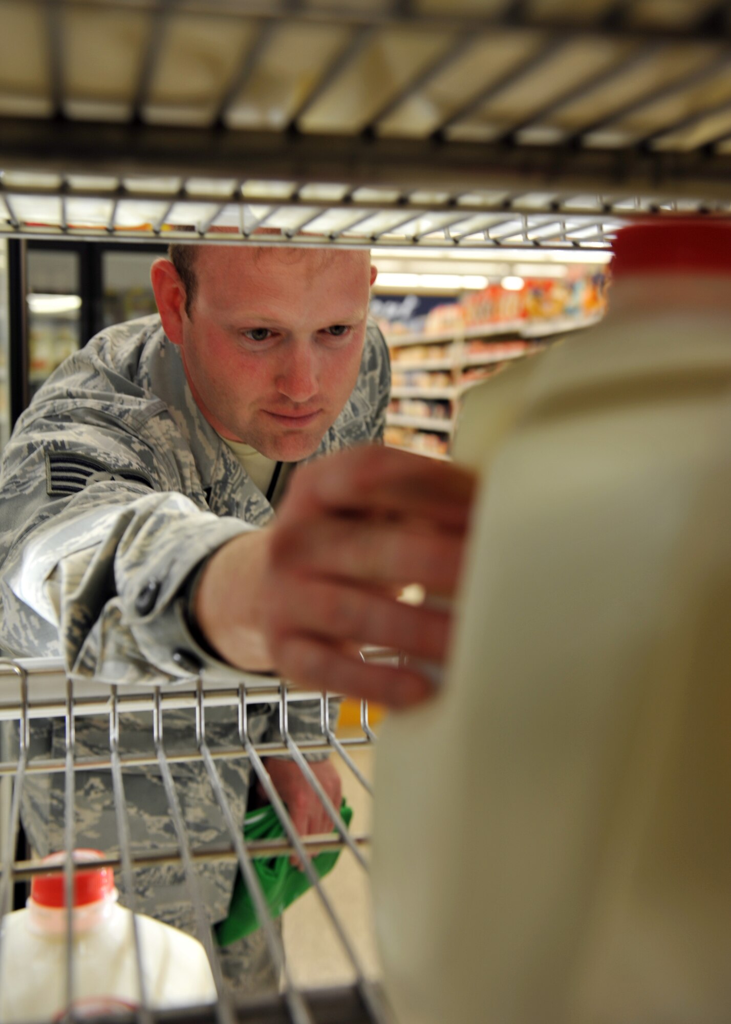 Staff Sgt. Brett Lodwick, 509th Munitions Squadron munitions systems craftsman, reaches for a gallon of milk to compare ingredients during a commissary tour at Whiteman Air Force Base, Mo., May 10, 2013. The Health and Wellness Center provides monthly tours of the commissary to familiarize Team Whiteman with the nutritional value of groceries they choices. (U.S. Air Force photo by Heidi Hunt/Released)