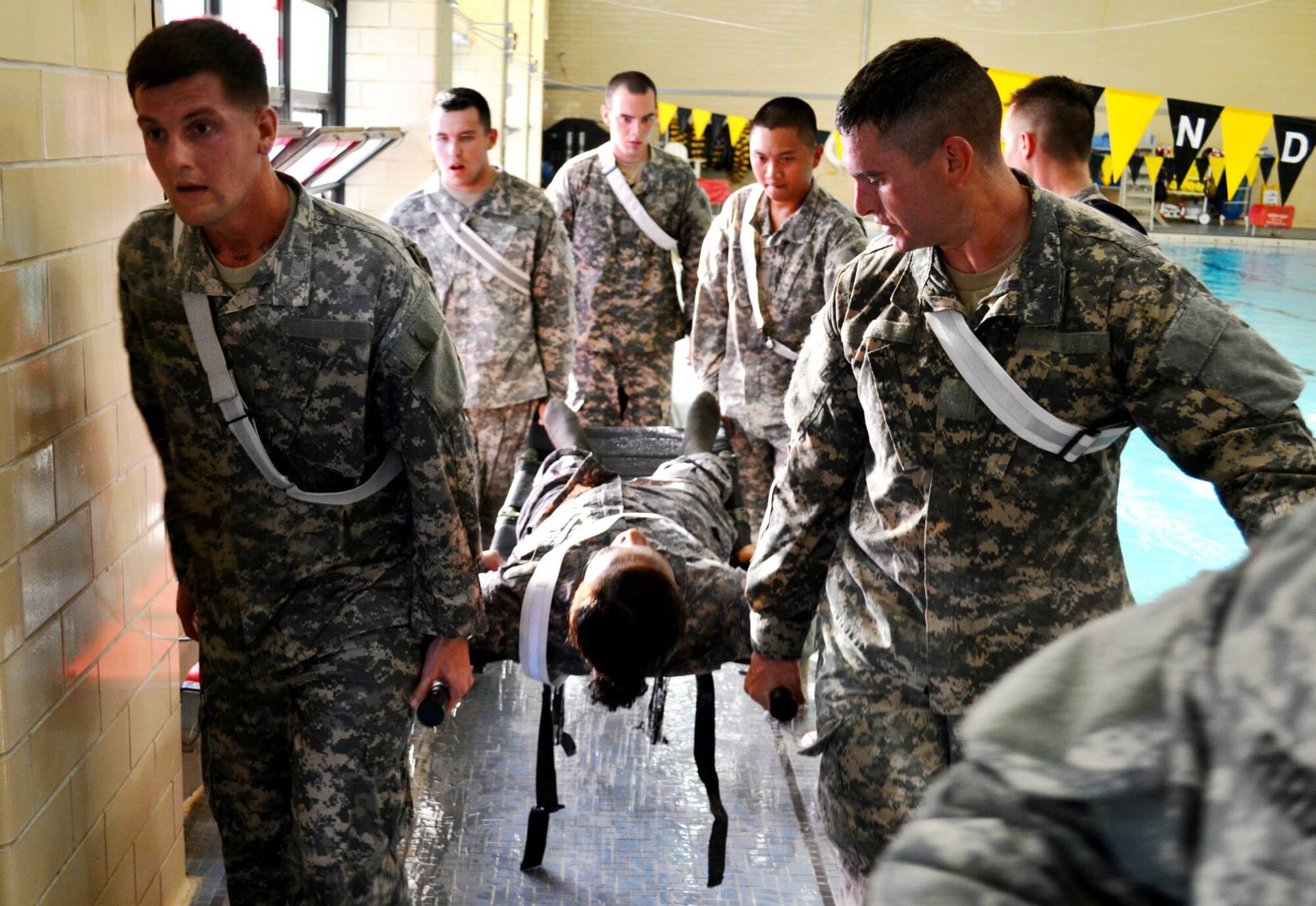 Soldiers from the 10th Transportation Battalion, 7th Sustainment Brigade carry a simulated casualty across an Olympic-sized swimming pool during a pre-dawn squad fitness competition at Fort Eustis, Va., May 17, 2013. The competition featured events such as litter carries, push-ups, pull-ups, sit-ups and a seven-mile ruck march, all designed to test the physical abilities of Soldiers in the battalion’s companies. (U.S. Army photo by Sgt. 1st Class Brian G. Rhodes/Released)