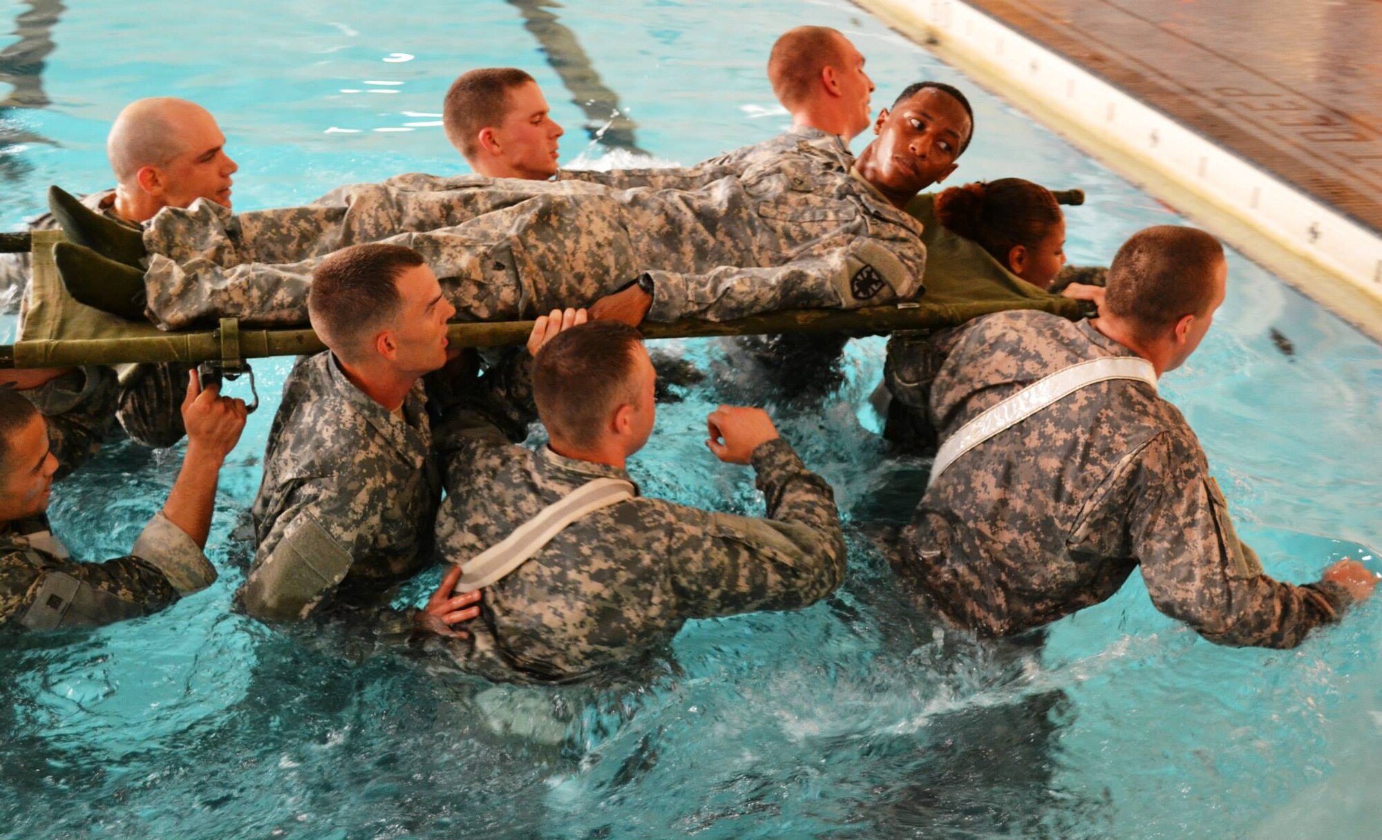 Soldiers from the 10th Transportation Battalion, 7th Sustainment Brigade carry a simulated casualty across an Olympic-sized swimming pool during a pre-dawn squad fitness competition at Fort Eustis, Va., May 17, 2013. The competition featured events such as litter carries, push-ups, pull-ups, sit-ups and a seven-mile ruck march, all designed to test the physical abilities of Soldiers in the battalion’s companies. (U.S. Army photo by Sgt. 1st Class Brian G. Rhodes/Released)