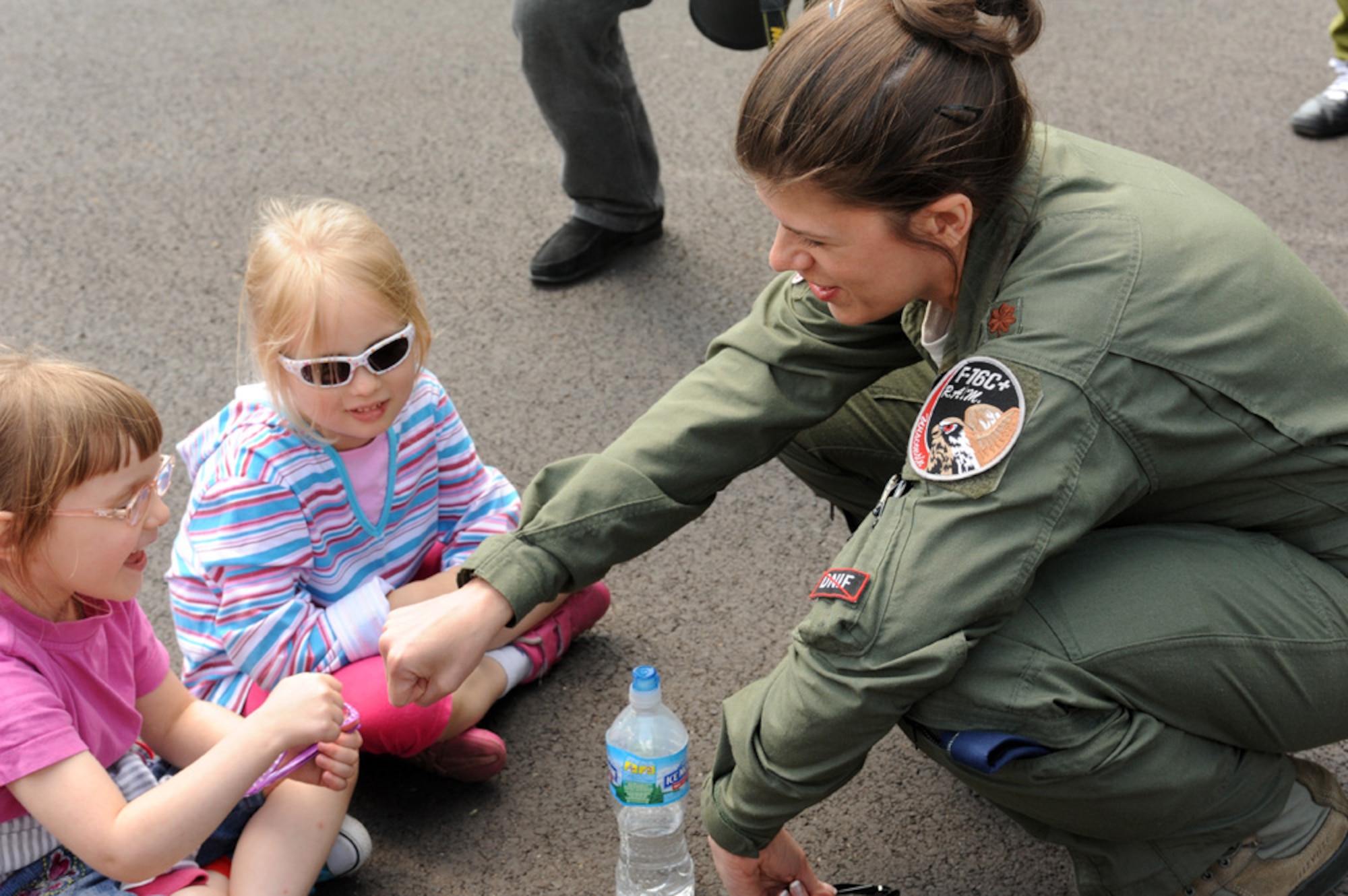 LASK AIR BASE, Poland - U.S. Air Force Maj. Karice Stern, 176th Fighter Squadron flight doctor assigned to the 115th Fighter Wing, Wisconsin Air National Guard, teaches two elementary school students how to "fist bump" during a community outreach day at Lask Air Base, Poland, May 15, 2013. Stern is among the nearly 100 Airmen who came to Poland to participate in a two week joint theater cooperation event hosted by Aviation Detachment 1, 52nd Operations Group. More than 50 children and teens from the local schools visited the base to view US and Polish fighter aircraft and interact with airmen from each allied nation. (U.S. Air Force photo by Tech. Sgt. Kenya Shiloh/released)