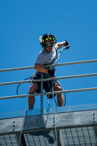 Staff Sgt. William Jenkins, 628th Civil Engineer Squadron Fire Department firefighter, pulls a fire hose to the top of the five-story fire training tower during the Police Week Guns and Hoses competition May 15, 2013, at Joint Base Charleston - Air Base, S.C. The 628th Security Forces Squadron hosted events including the "Guns and Hoses" fitness challenge, a shooting competition, chili cook-off and a retreat ceremony. National Police Week recognizes the services and sacrifices of U.S. law enforcement personnel. (U.S. Air Force photo/ Senior Airman George Goslin)