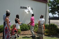 The family of the late Air Force Maj. Peter "Oly" Jahns, a former T-38 instructor pilot, pulls down a banner to reveal Jahns Hall after the 39th Flying Training Squadron building dedication ceremony Friday at Joint Base San Antonio-Randolph. Jahns died in a T-38 crash March 19, 2003, during a routine training flight at Randolph. (Air Force photo by Richard McFadden)