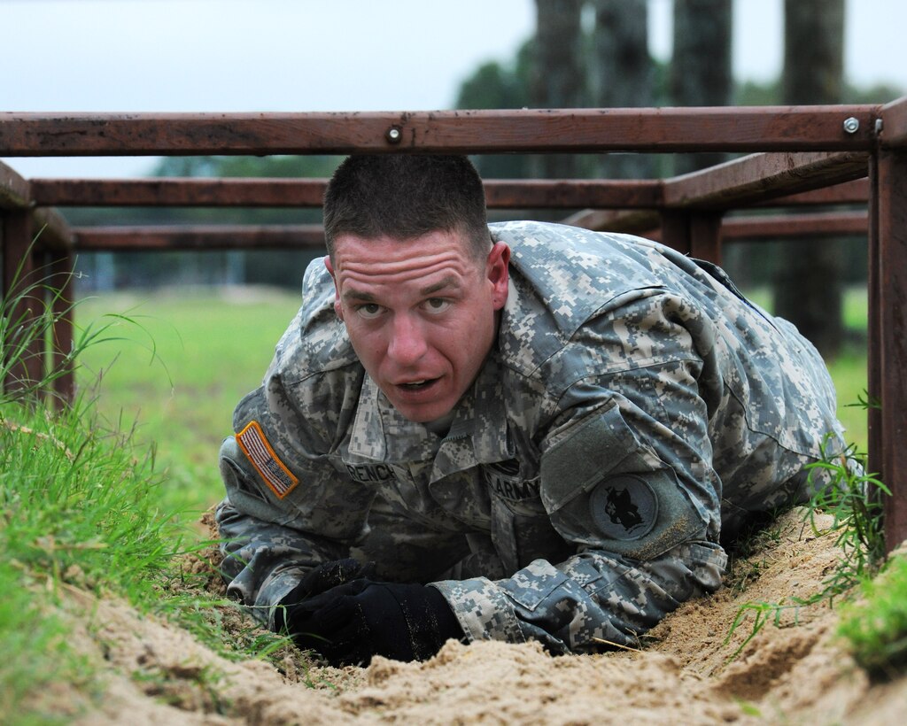 Army Sgt. Andrew French crawls through an obstacle course during the ...