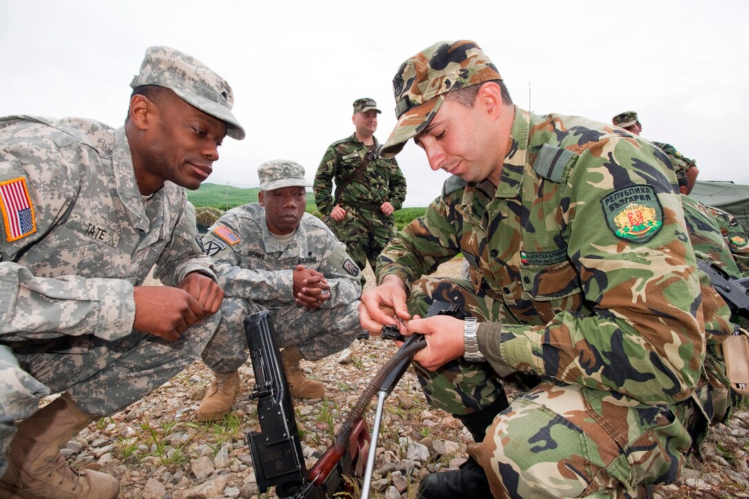 U.S. Army Spc. Tate, left, and U.S. Army Staff Sergeant Spinks, center, watch as Bulgarian soldiers clean and check a weapon during Thracian Guard 2013 on Novo Selo Training Area, Bulgaria, May 14, 2013. 