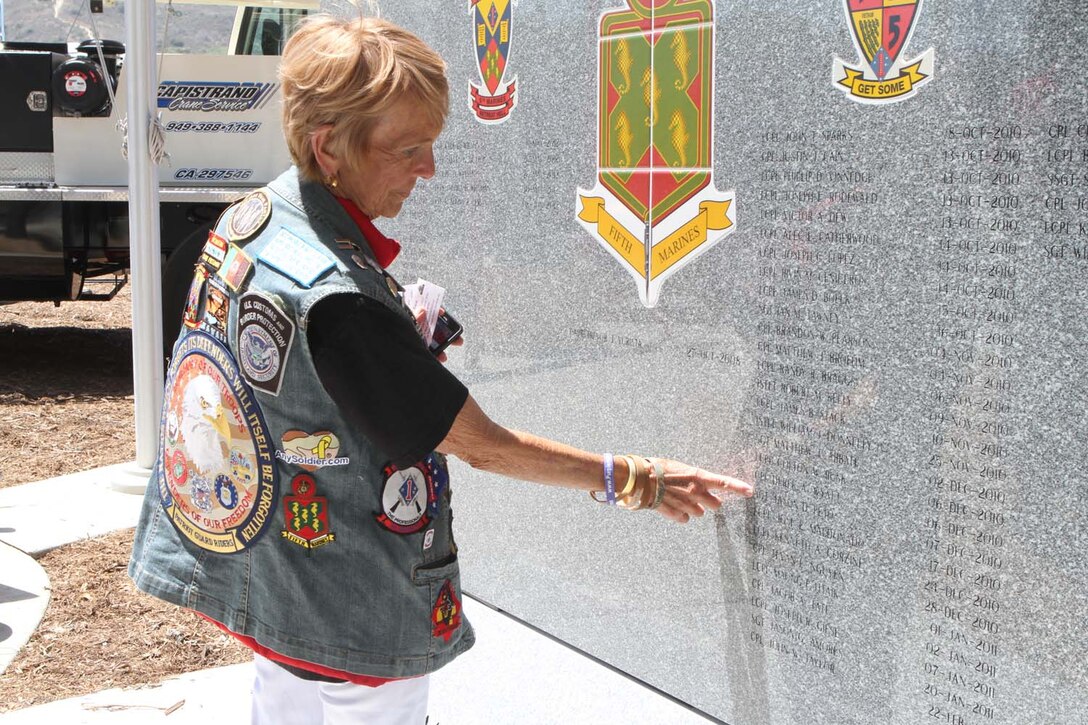 Peggy Kane, a southern California Patriot Guard Rider, points to a family friend who died in support of Operation Enduring Freedom on the 5th Marine Regiment's Operation Enduring Freedom Memorial at Camp San Mateo's Memorial Garden here, May 20, 2013. Members of the Patriot Guard Riders escorted the 7-ton, Barre granite memorial from Barre, Vt., to Camp Pendleton during the course of 10 days.