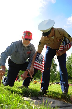 Sgt. Manuel Bermudez, supply clerk with the 9th Marine Corps District, joins Merlyn Teigen, a member of the Simpson Hoggat Marine Corps League detachment, in placing a flag on the grave of a veteran, May 23. Several Marines and members of the Simpson Hoggat detachment gathered at Mt. Moriah South Cemetery to place dozens of American flags on the graves of veterans.