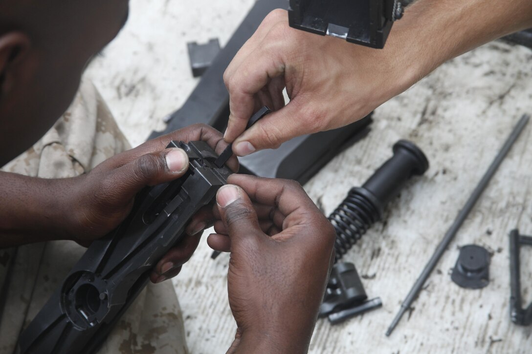Lance Cpl. Darby S. Weiss, a motor vehicle operator with MWSS-274, assists Lance Cpl. Kaheem J. Sharpe, an automotive organizational mechanic with MWSS-274, as he assembles the bolt group of an M2 .50-caliber machine gun during the Machine Gun Assistant Instructor Course at the Basic Skills Training School aboard Camp Lejeune Monday.