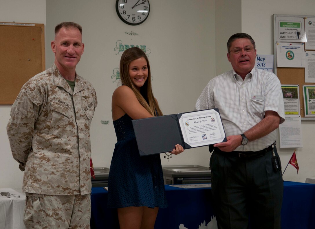 Marine Corps Air Station Yuma's commanding officer Col. Robert C. Kuckuk stands alongside Morgan C. Frank as she is awarded the scholarship at the recognition ceremony, in which the Defense Commissary Agency recognized the Scholarships for Military Children Recipient at MCAS Yuma's Commissary, the afternoon May 23