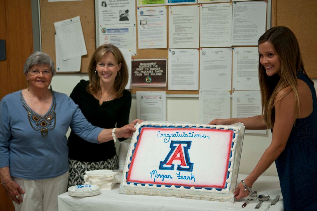 Morgan C. Frank, and her mother and grandmother, stand by the cake in honor of the Marine Corps Air Station Yuma's Commissary holding a recognition ceremony, in which the Defense Commissary Agency recognized the Scholarships for Military Children Recipient, May 23.