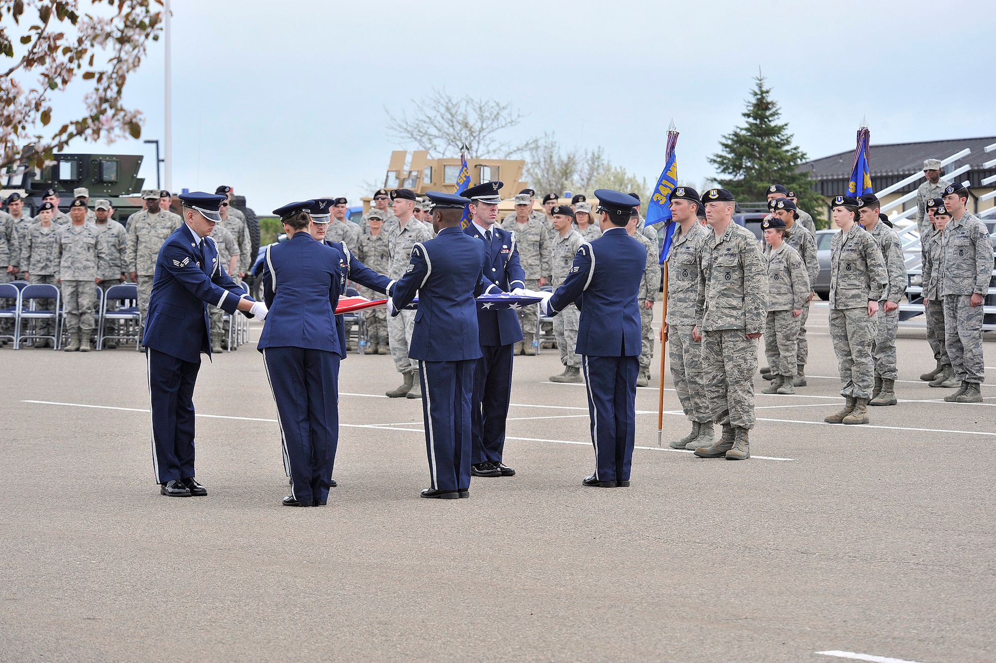 Members of Malmstrom’s Honor Guard fold a flag as Airmen across the base stand at attention during a formal Retreat Ceremony in celebration of National Police Week.  The week-long observation also included a security forces demonstration, 5K run and police vehicle parade.  (U.S. Air Force photo/John Turner)