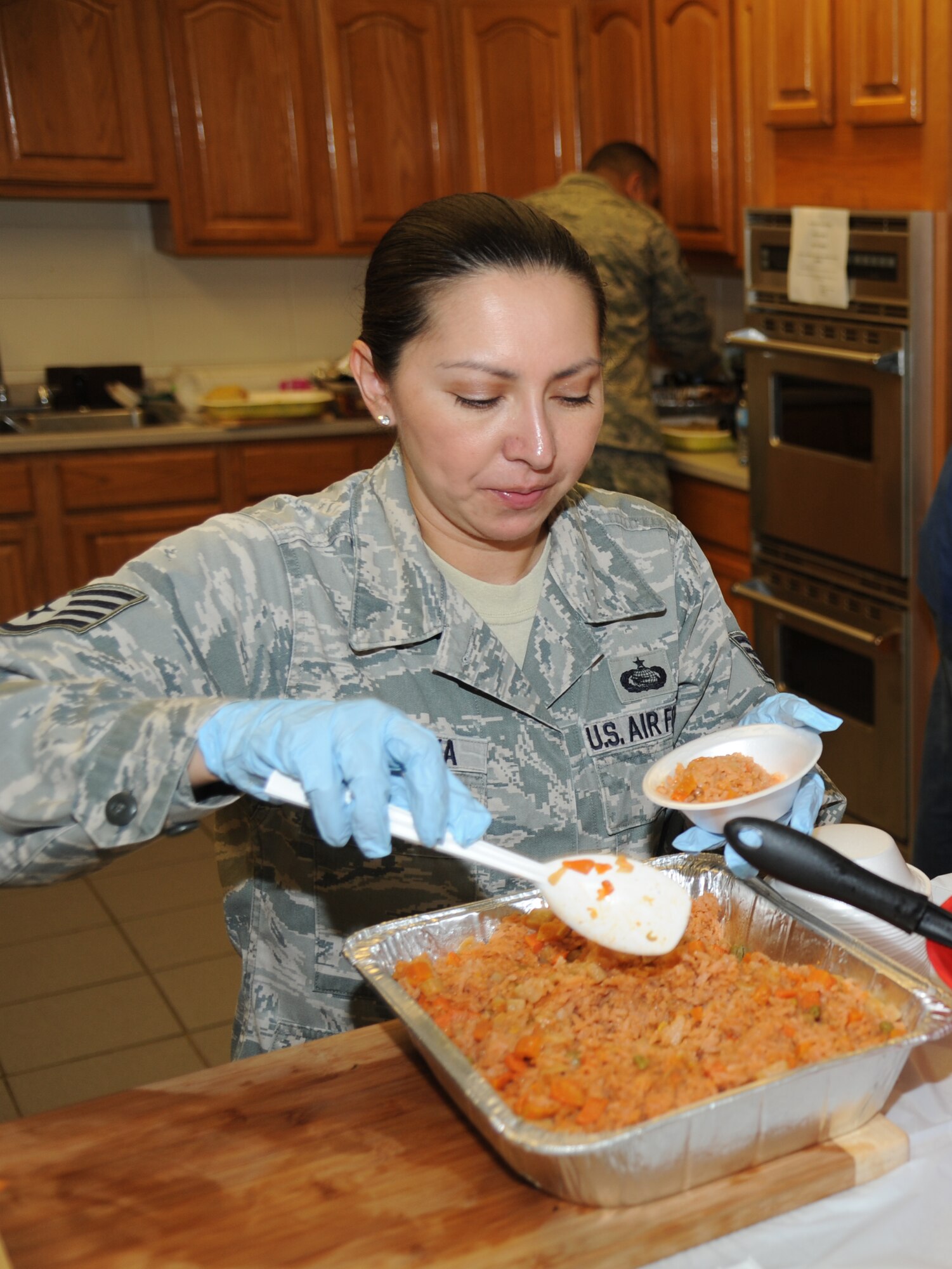 Staff Sgt. Yazmin Montoya, 81st Force Support Squadron, fill bowls with rice and beans during the Latin-American Heritage Committee food sampling May 23, 2013, at the marina, Keesler Air Force Base, Miss.  The event also included a variety of beverages and music to showcase diversity on base.  (U.S. Air Force photo by Kemberly Groue)