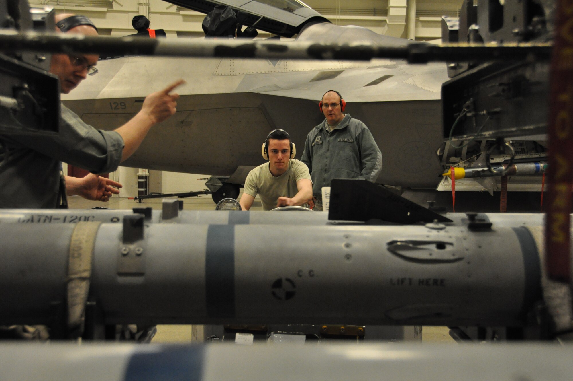 Tech. Sgt. Anthony Cords evaluates Senior Airman Joshua Baker as he picks up an AIM-120 air-to-air missile with a jammer while Tech. Sgt. Timothy Tuttle gives him directions during the 2012 JBER F-22 Weapons Load Competition. Tuttle and Baker are both Reserve weapons loaders assigned to the 477th Aircraft Maintenance Squadron. Their three man crew was recently awarded the 2012 JBER F-22 weapons load crew of the year.(U.S. Air Force/ Tech. Sgt. Dana Rosso)
