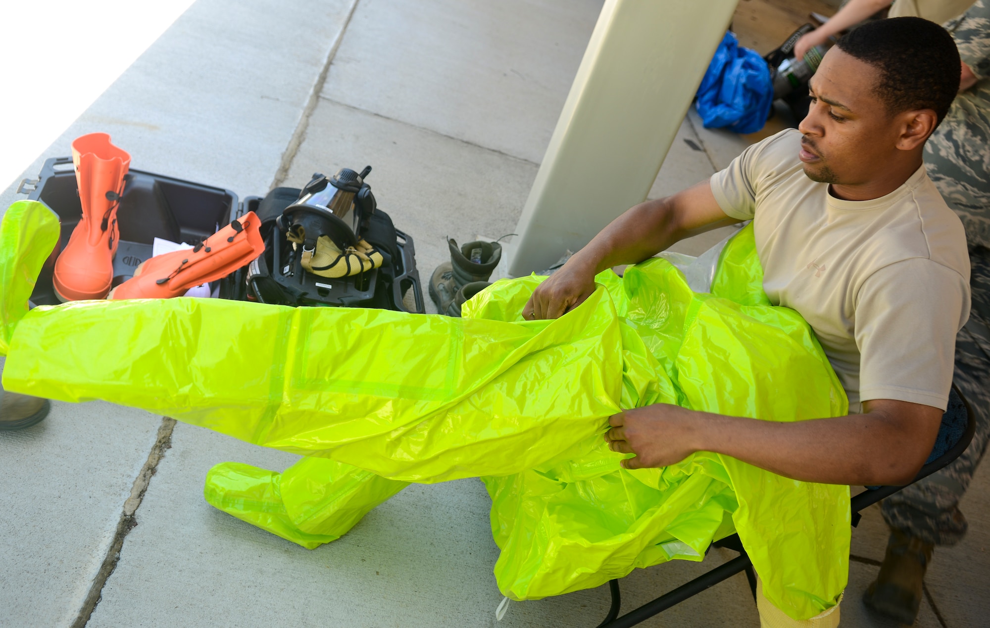 U.S. Air Force Senior Airman Ronell Tennant, 633rd Civil Engineer Squadron emergency management technician, suits up before going inside a contaminated building during a training exercise at Langley Air Force Base, Va., May 16, 2013. During the exercise and in real-life scenarios, a bioenvironmental technician aids the emergency management technician in gathering important data from the incident site. (U.S. Air Force photo by Airman 1st Class Austin Harvill/Released)