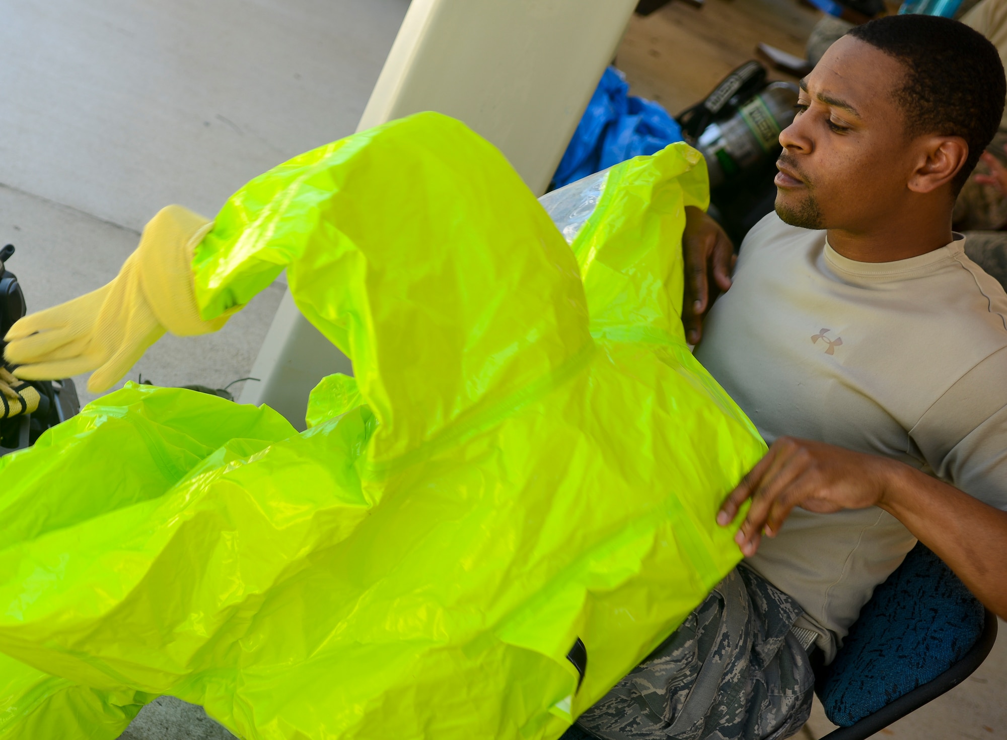 U.S. Air Force Senior Airman Ronell Tennant, 633rd Civil Engineer Squadron emergency management technician, suits up before going inside a contaminated building during a training exercise at Langley Air Force Base, Va., May 16, 2013. During the exercise and in real-life scenarios, a bioenvironmental technician aids the emergency management technician in gathering important data from the incident site. (U.S. Air Force photo by Airman 1st Class Austin Harvill/Released)