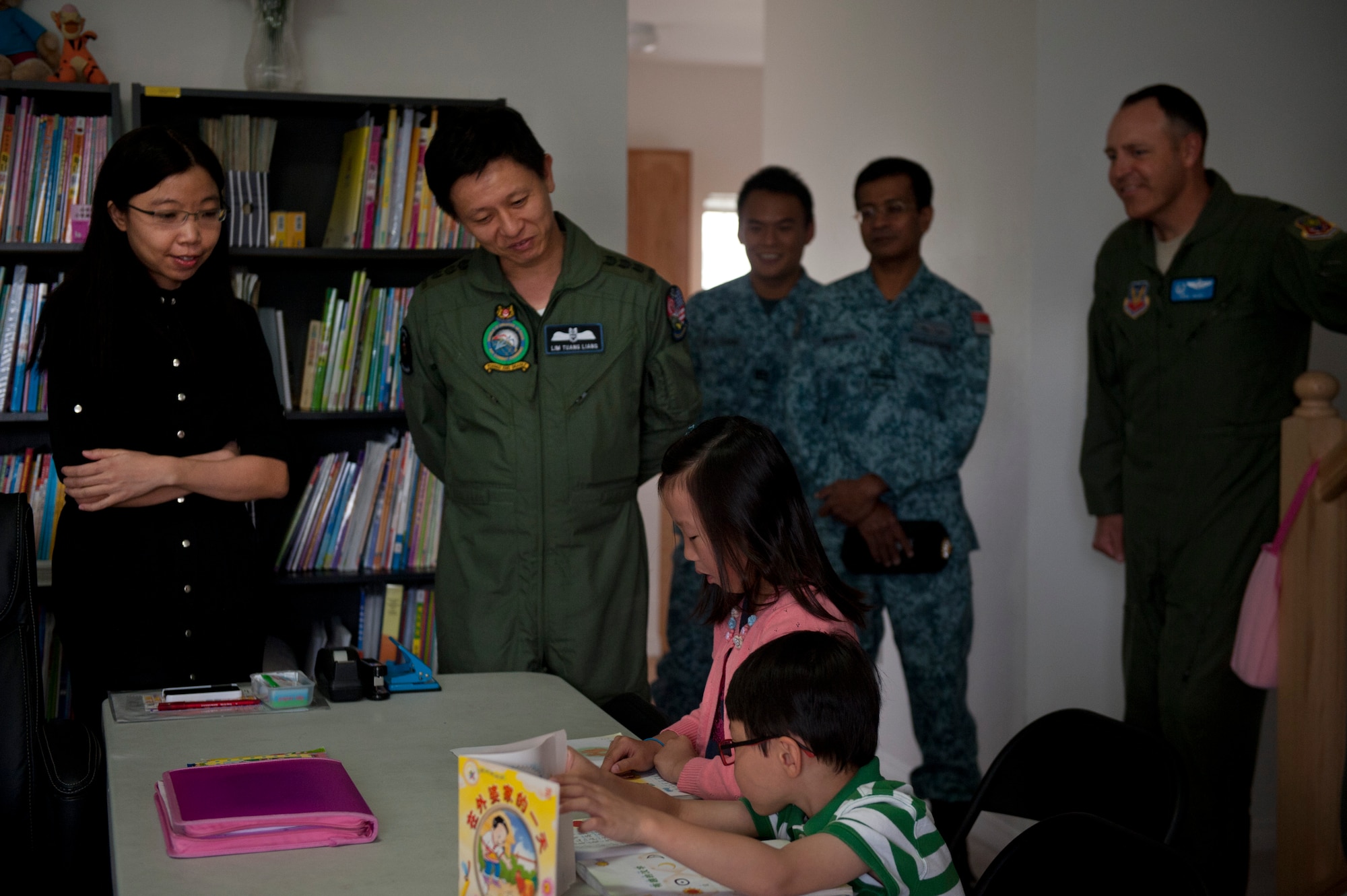 Republic of Singapore’s Air Combat Command Commander Col. Lim Tuang Liang listens as a student learning Chinese reads from a book May 16, 2013 at Mountain Home Air Force Base, Idaho. The base housing unit has been designated as a school to teach Chinese to children from Singapore. (U.S. Air Force Senior Airman Heather Hayward/Released)