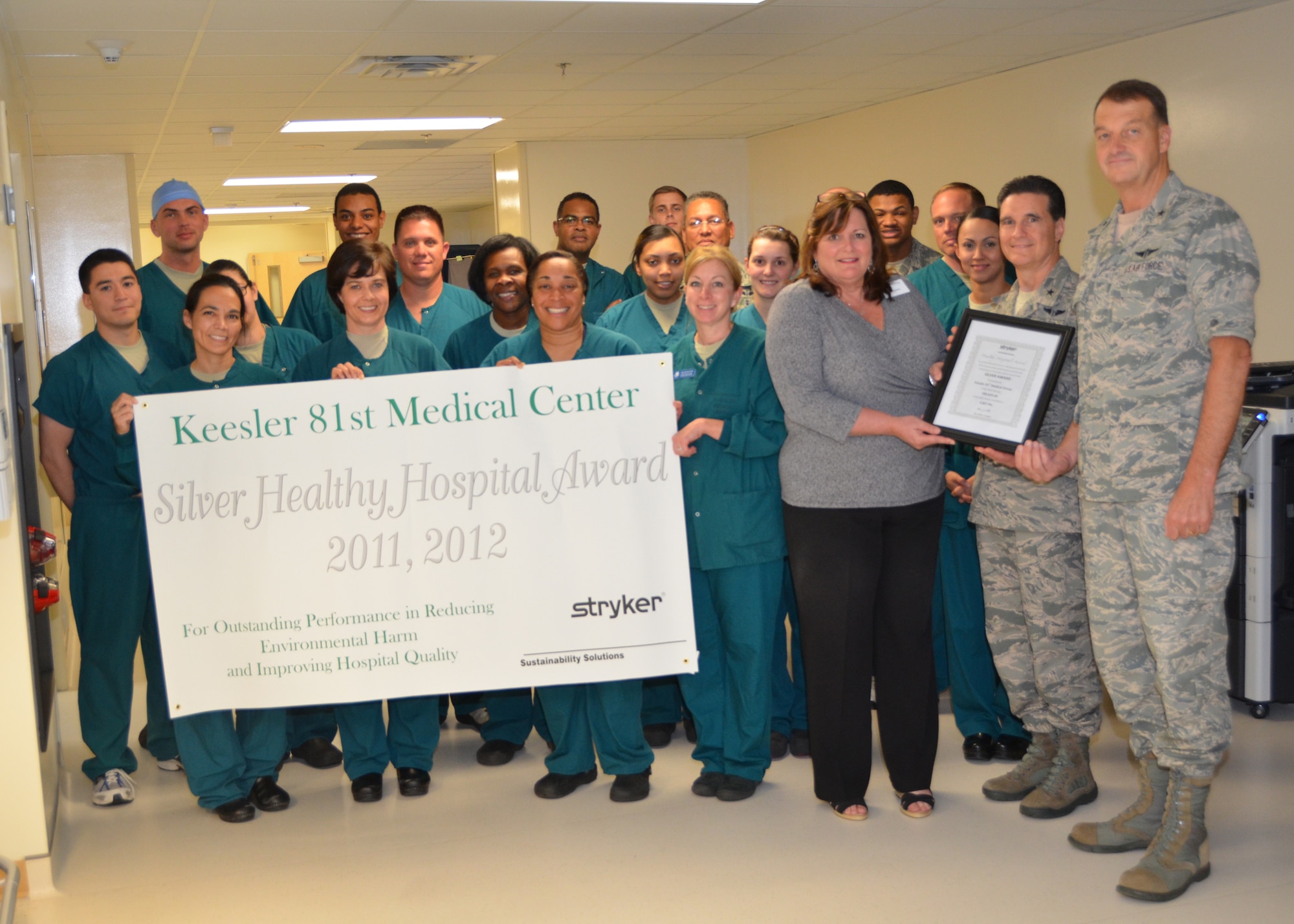 Members of the 81st Surgical Operations Squadron Operating Room Flight hold the banner signifying they had earned the Stryker Sustainability Solutions “Silver Healthy Hospital Award” for 2011 and 2012 as Joan Sullivan, the company’s account manager for Keesler, presents the award certificate to Brig. Gen. (Dr.) Sean Murphy, Air Force Medical Operations Agency commander, second from right, and Brig. Gen. (Dr.) Kory Cornum, Keesler Medical Center commander, right, May 8 outside the Back Bay Tower operating rooms. Murphy was visiting the medical center from his San Antonio headquarters. (U.S. Air Force photo by Steve Pivnick)