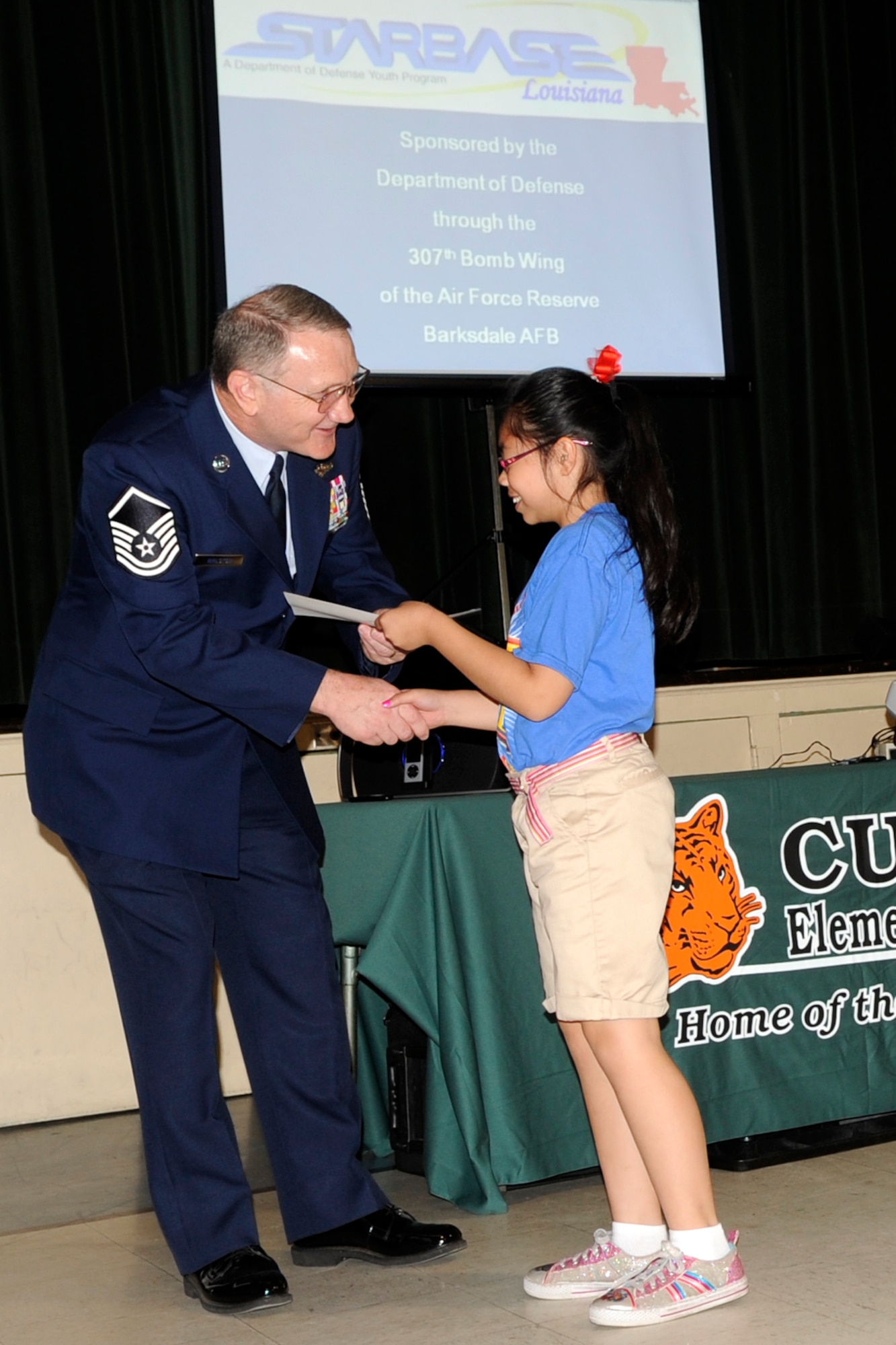 Master Sgt. Jeff Walston, a public affairs technician assigned the 307th Bomb Wing, Barksdale Air Force Base, La., congratulates and presents a certificate to a 5th Grade student at Curtis Elementary school in Bossier City, La., May 22, 2013. Walston was the guest speaker for a STARBASE graduation ceremony at the school.  The students completed an exciting 25-hour hands on/minds on aviation and aerospace course offered to area 5th grade students and their teachers by STARBASE Louisiana, at Barksdale. The program is one of 70 national STARBASE sites, and is sponsored by the 307th BW of the Air Force Reserve Command. Many U.S. Air Force servicemembers volunteer to speak at the graduation ceremonies to help motivate the students to continue their education. This was Walston’s fifth graduation ceremony. Speakers are always welcomed and always needed. Any officer or senior non-commissioned officer interested in motivating these young people should contact the 307th Bomb Wing Public Affairs Office at 318-529-3023 to be put on the speaker’s list. (Courtesy photo by Eva Klimentova)