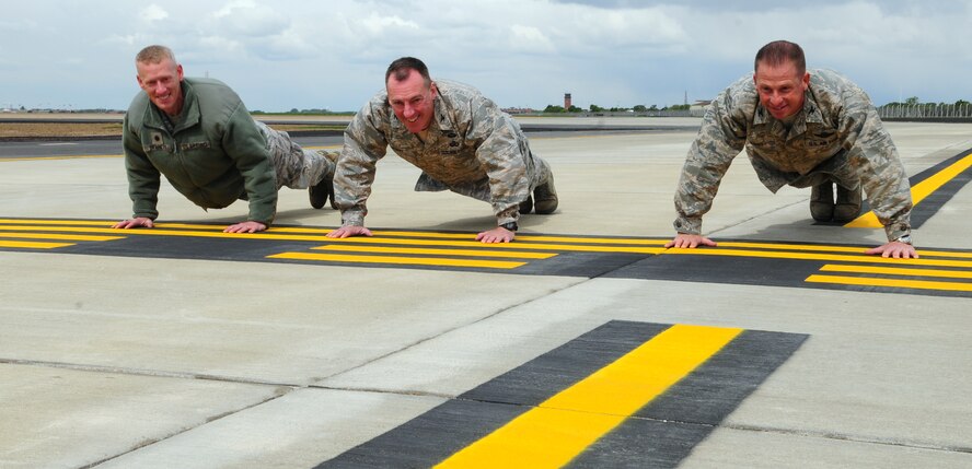 From left, Lt. Col. Chris Bennett, 100th Operations Support Squadron commander; Col. Daniel Merry, 100th Mission Support Group commander; and Col. Kyle Voigt, 100th Air Refueling Wing vice commander, perform push-ups on the hold line of Taxiway Echo, after it officially opened May 23, 2013, on RAF Mildenhall, England. Service members from the 100th ARW, along with contractors from the company who built the taxiway extension, attended the ribbon-cutting ceremony which marked the opening of Taxiway Echo, an extension to Taxiway Alpha. (U.S. Air Force photo by Karen Abeyasekere/Released)
