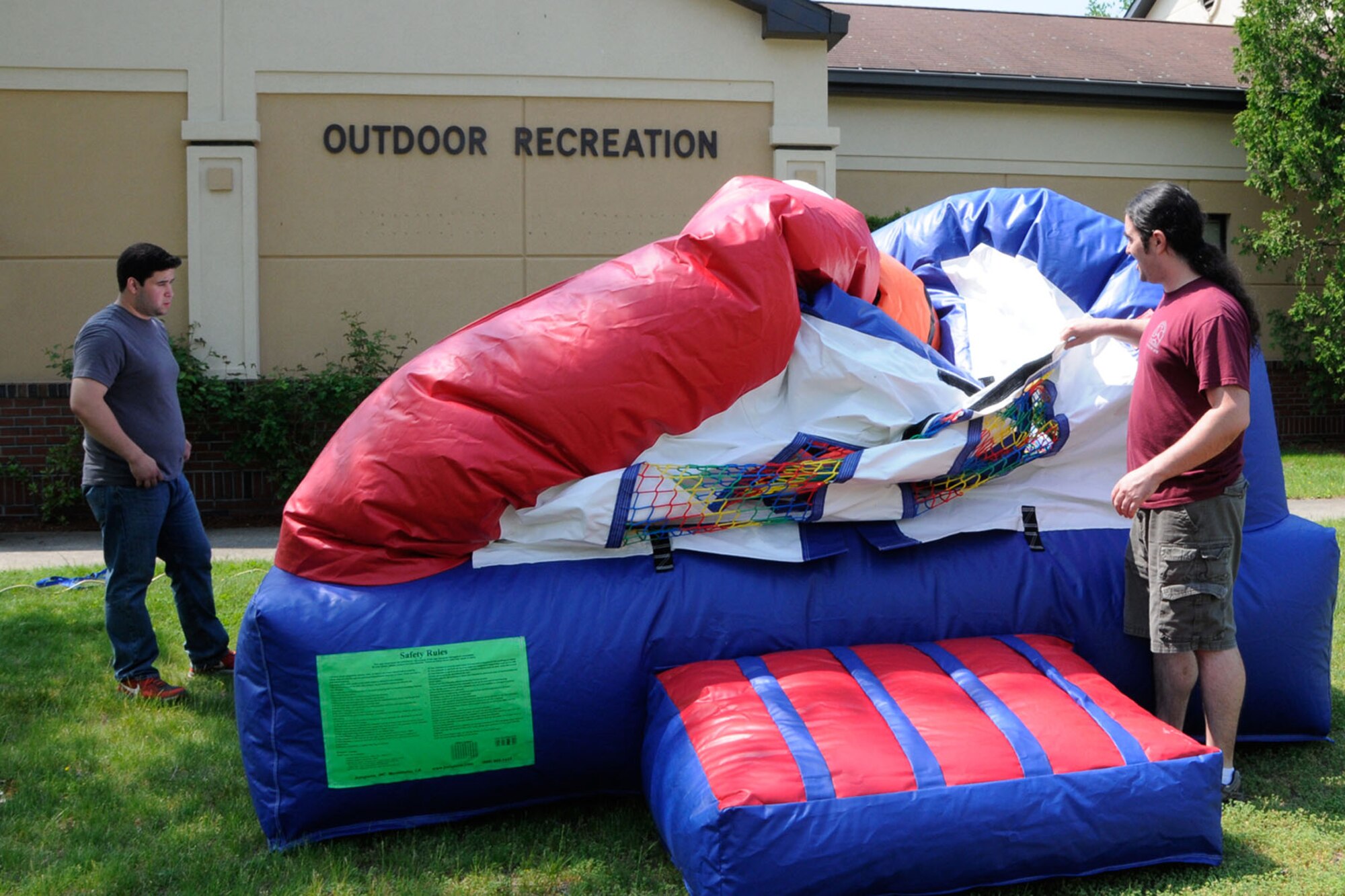 HANSCOM AIR FORCE BASE, Mass. – Outdoor Recreation employees Brian Guerra (left) and Brad Lavoie set up an outdoor bounce house for summer fun, May 21. Outdoor Recreation offers a wide range of sporting, camping, boating and party equipment available for the Hanscom community to rent. (U.S. Air Force photo by Linda LaBonte Britt)