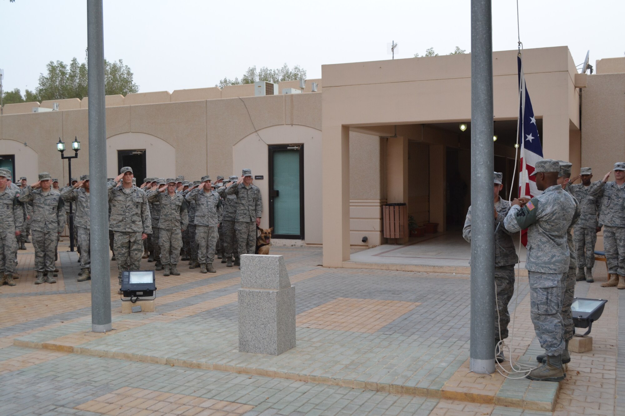 The U.S. Flag is lowered while members of the 64th Air Expeditionary Group render a salute during the retreat ceremony as part of Police Week activities at Eskan Village in Southwest Asia, May 15, 2013. Other activities included a 5K run and an “Amazing Race” event. (U.S. Air Force photo/Staff Sgt. Jason Colbert)