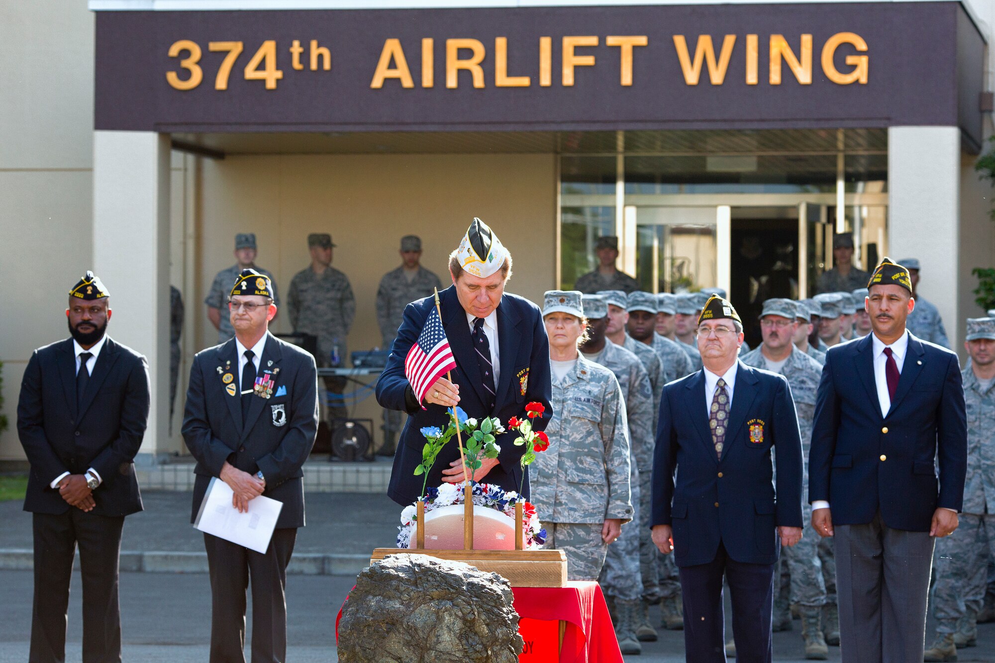 YOKOTA AIR BASE, Japan -- Dr. Tim Williams, a member of Veterans of Foreign War Post 9555, presents the American flag to a monument honoring fallen service members during the Memorial Day ceremony at Yokota Air Base, Japan, May 23, 2013. Men and women from Yokota attended the ceremony to remember the contributions made to the nation by service members. (U.S. Air Force photo by Osakabe Yasuo) 
