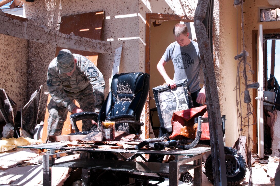 Air Force Senior Master Sgt. Kevin Tucker, left, and his son, Air Force Senior Airman Brandon Tucker, right, begin the process of clearing out debris from the son's home in Moore, Okla., May 22, 2013. The house was severely damaged after a devastating tornado killed dozens of people there, May 20. Senior Master Sgt. Tucker, a public affairs sergeant, is assigned to the 137th Air Refueling Wing, and Senior Airman Tucker, a crew communication specialist, is assigned to the 185th Air Refueling Squadron.