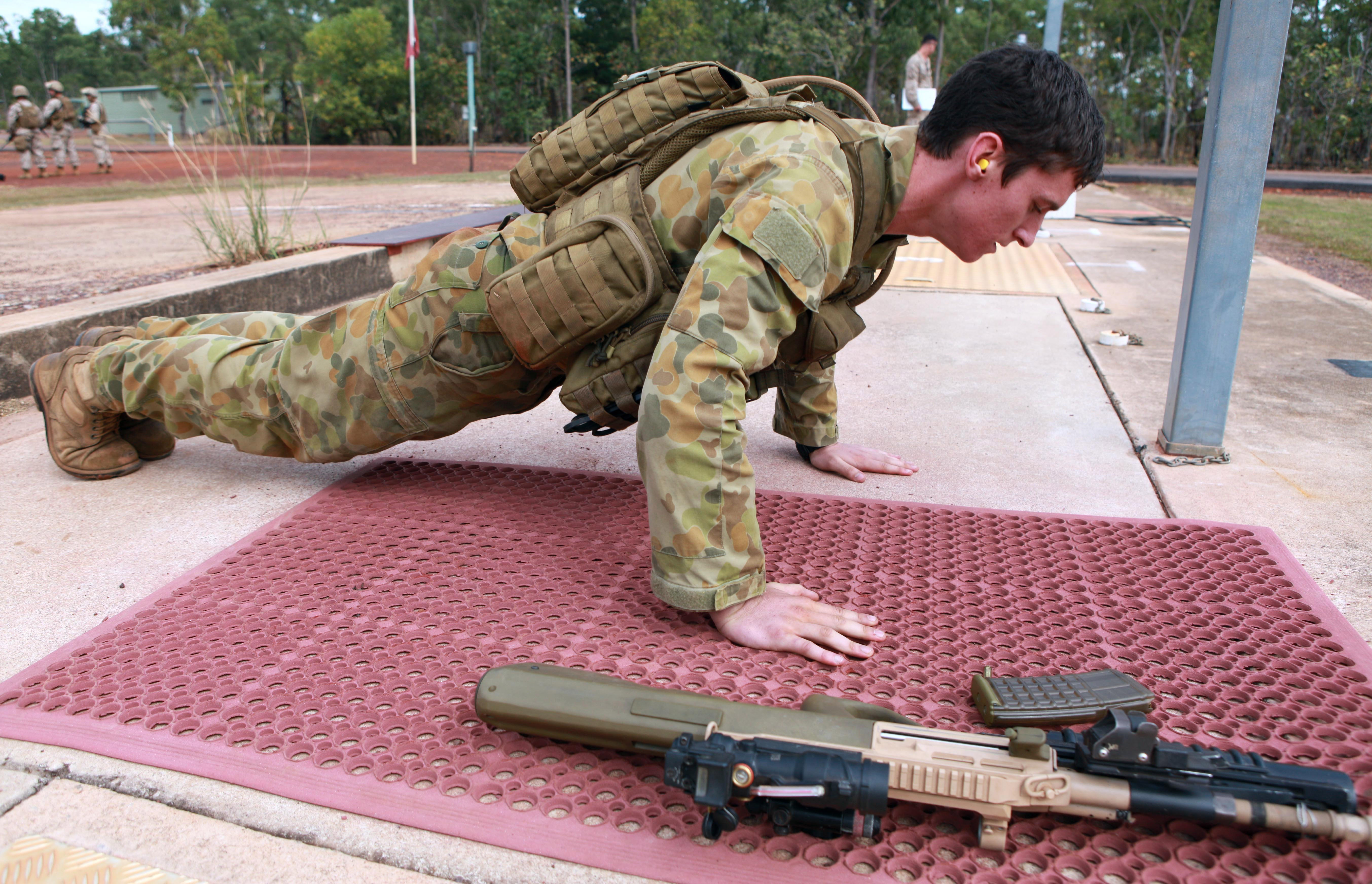 Australian army Pvt. Jake Budge push-ups before shooting target with an F88