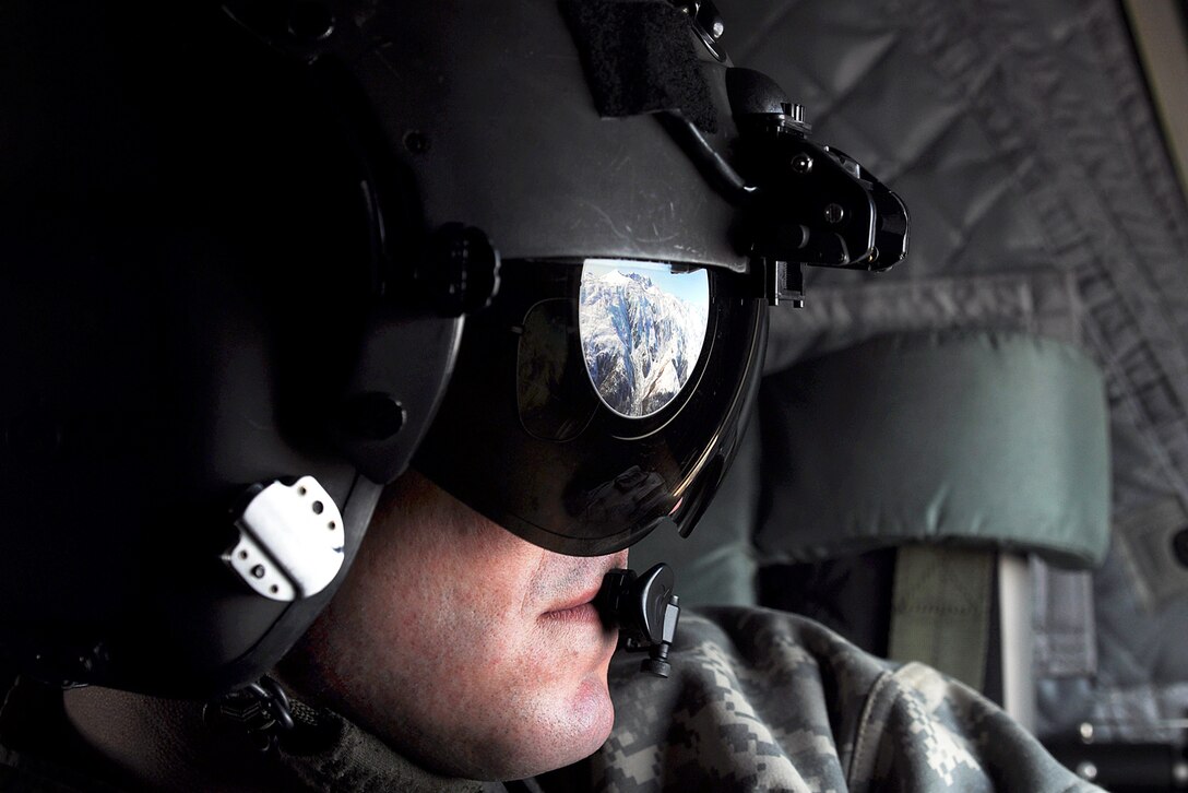 The Alaska Range reflects off Army Staff Sgt. Evan Sutton's visors as he watches for danger while his CH-47 Chinook helicopter flies along the range on its way to Kahiltna Glacier, Alaska, May 20, 2013. Sutton and the helicopter crew transported a team of eight soldiers and one Army civilian from Fort Wainwright to the National Park Service base camp on the glacier to begin their attempt to climb Mount McKinley, North America's tallest peak.