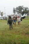 Command Sgt. Maj. Ricky Griffin of the Louisiana National Guard leads a group of stranded citizens to National Guard helicopters who then transport them from Hackberry, La., to the Million Air hangar at Chennault Airport in Lake Charles. From there Wildlife and Fisheries agents assisted them in making contact with friends and relatives who could pick them up.