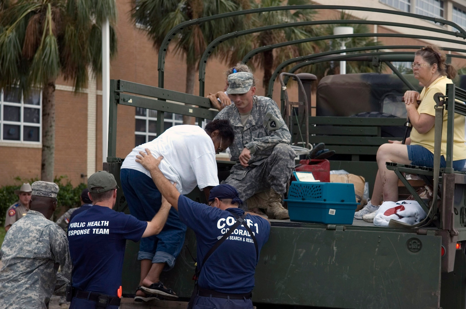 Joint responders assist people from five-ton vehicles at a local high school in Galveston, Texas, before being be bused to San Antonio.