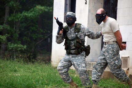 A warrant officer candidate (left) escorts another candidate through the military training in urban terrain (MOUT) training site at Fort McClellan, Ala. The candidates, armed with paintball guns, maneuver through the urban terrain while reacting to direct and indirect fire. The candidate on the right is simulating an enemy hostage. Candidates must learn to deal with the realities of today's urban warfare.