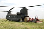 National Guardsmen help guide a local rancher as he loads bundles of hay aboard a CH-47 Chinook helicopter to deliver to stranded livestock who have been trapped by the flooded salt-waters without food or fresh water since Hurricane Ike struck the Southwest coast of Louisiana.